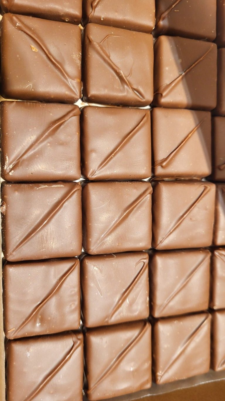 Carrés de chocolat brun empilés, avec une texture lisse et brillante.